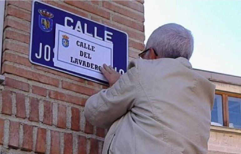 Un vecino pega el nombre de la calle aprobado sobre la placa franquista