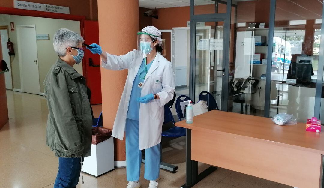 Auxiliar de enfermería toma la temperatura a una persona que llega al hospital