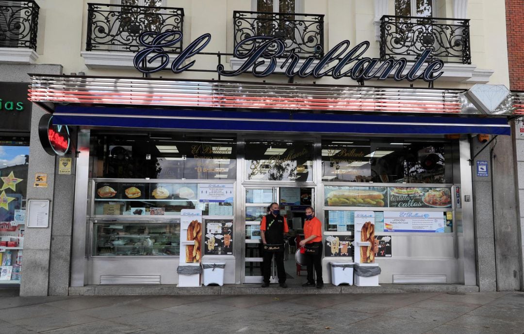 Dos personas ante el bar Brillante de Madrid en la mañana de este sábado otoñal de un fin de semana largo con lunes festivo incluido en la que la comunidad se encuentra en confinamiento perimetral.