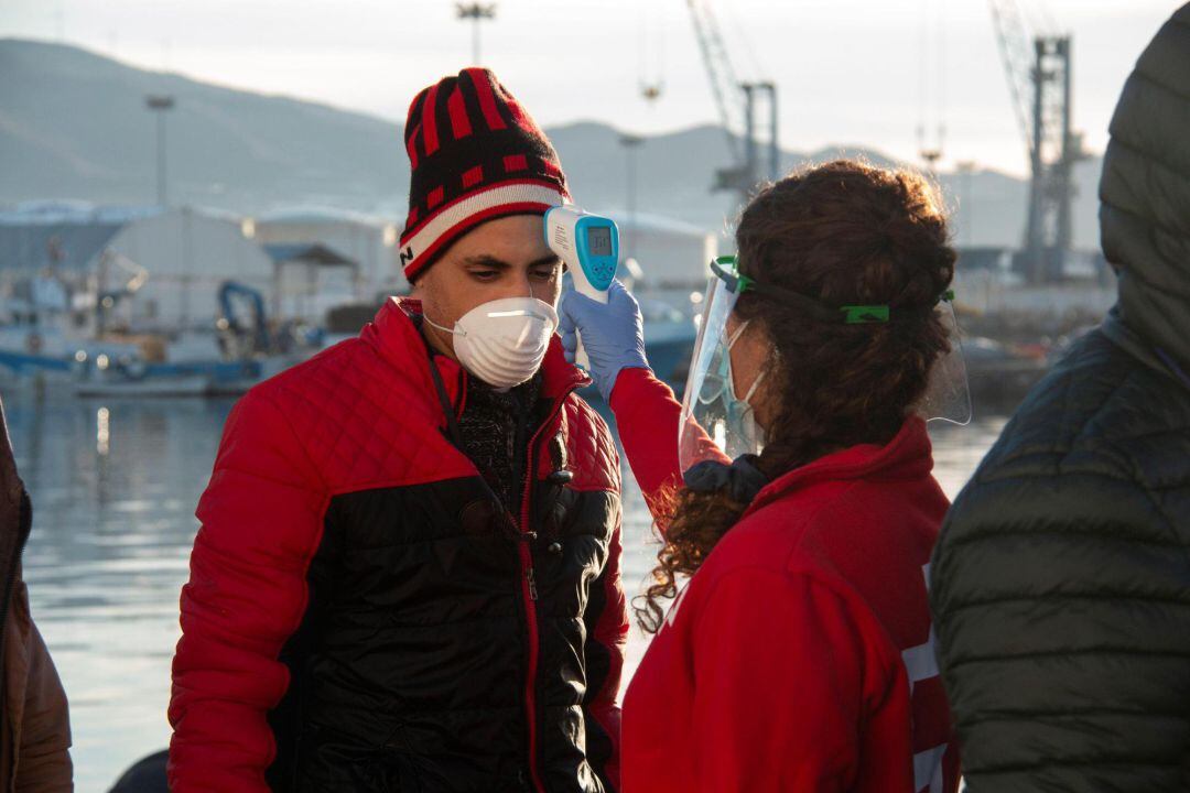 Voluntaria de Cruz Roja toma la temperatura a uno de los inmigrantes trasladados al Puerto de Motril