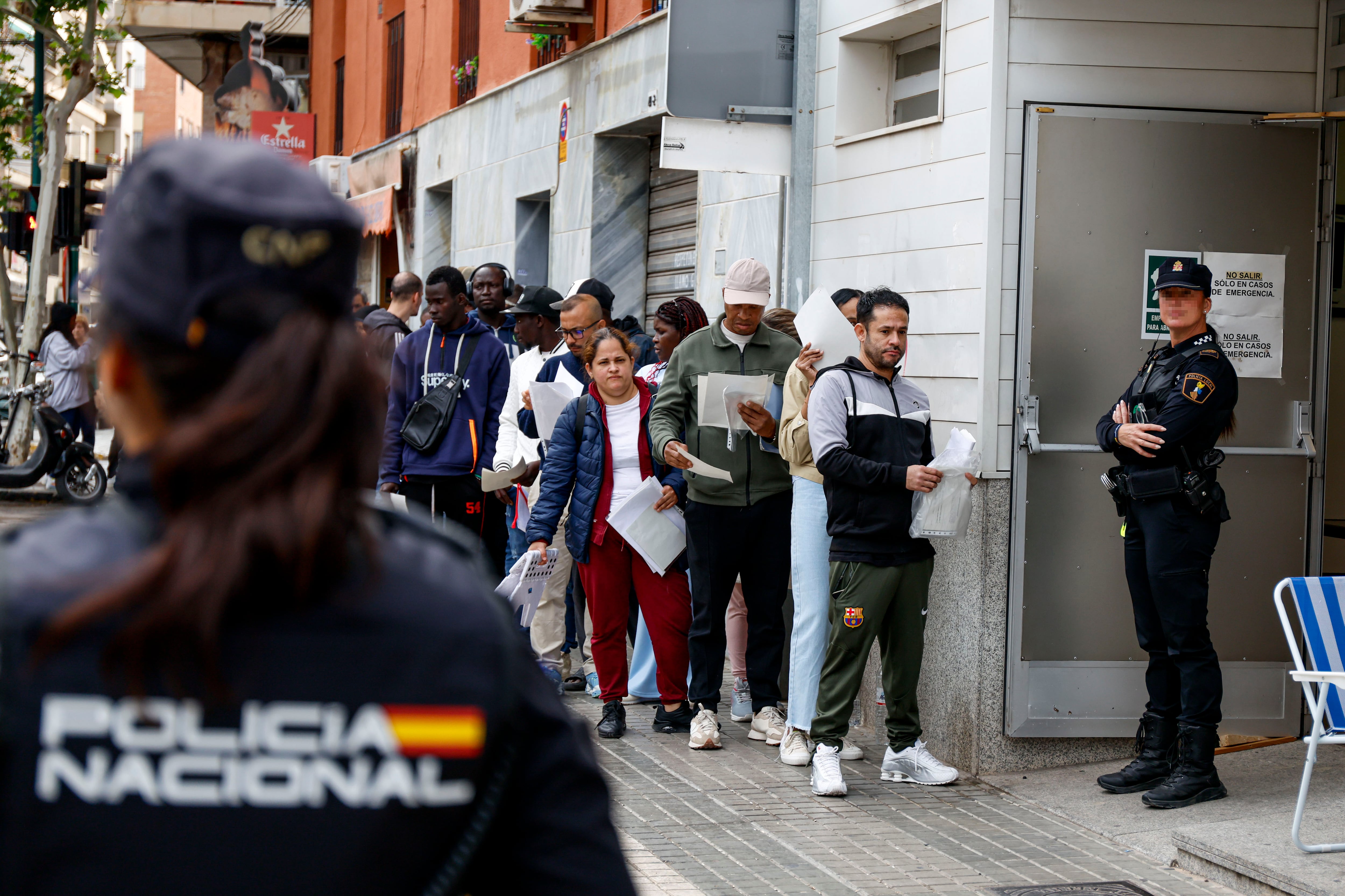 Decenas de personas hacen cola a las puertas de una Oficina de Atención a la Ciudadanía para presentar documentación dentro de su proceso de regularización. EFE/Pablo Miranzo