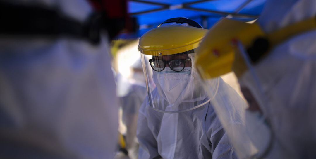 A health workers wearing protective gear talk at a drive-thru COVID-19 testing site