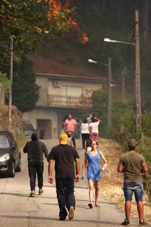 Varios vecinos miran las llamas cerca de una vivienda en el incendio forestal registrado en el sur de Galicia, en Soutomaior (Pontevedra), que se ha originado sobre las cuatro de esta tarde. Un amplio dispositivo, formado por agentes, brigadas y medios aé