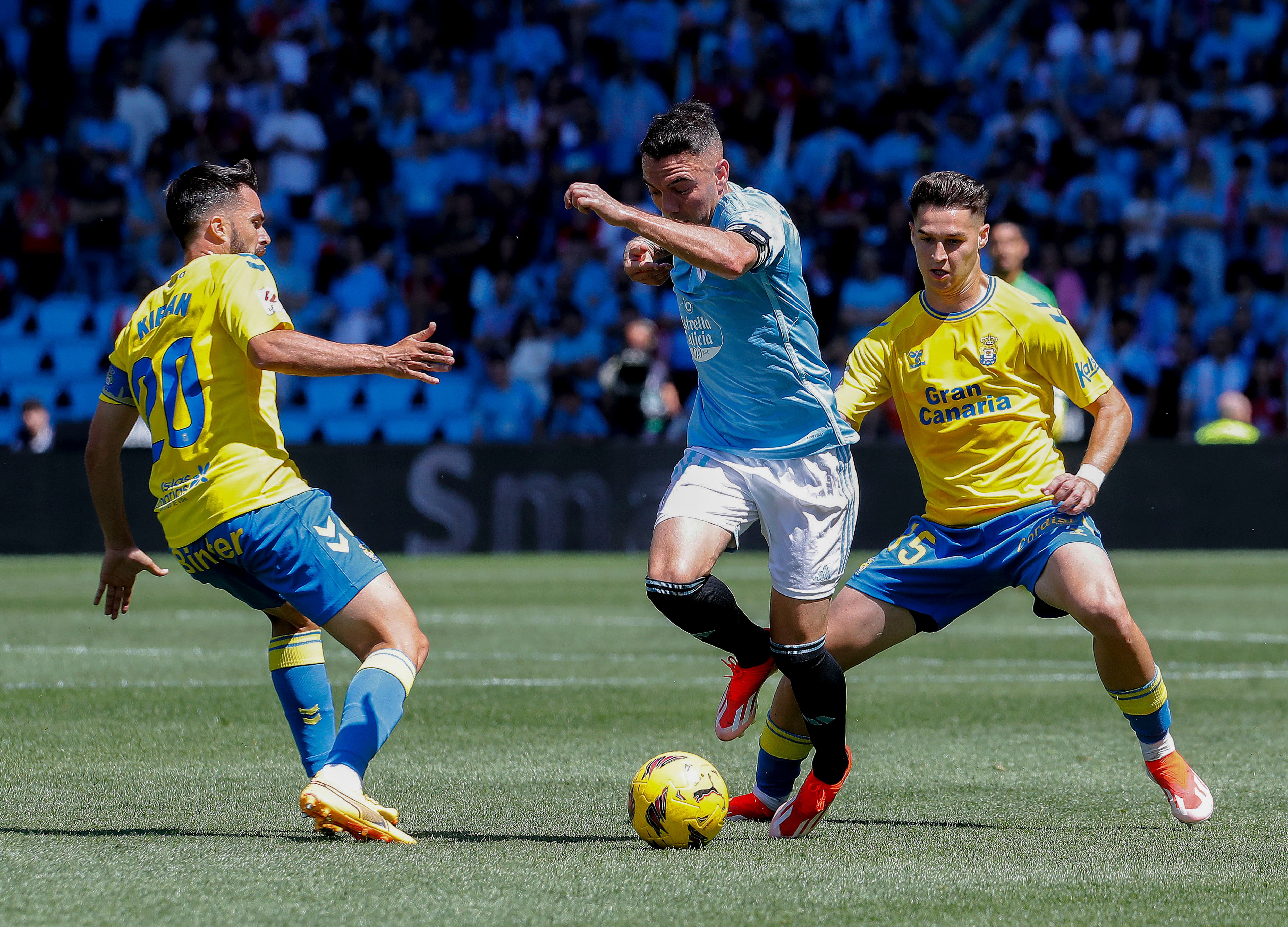 Vigo (Pontevedra) 20/04/2024.- El jugador del Celta de Vigo Iago Aspas (c) disputa el balón con Kiriam y Mármol (d), de Las Palmas, durante el partido de Liga celebrado este sábado en el estadio Balaídos de Vigo. EFE / Salvador Sas
