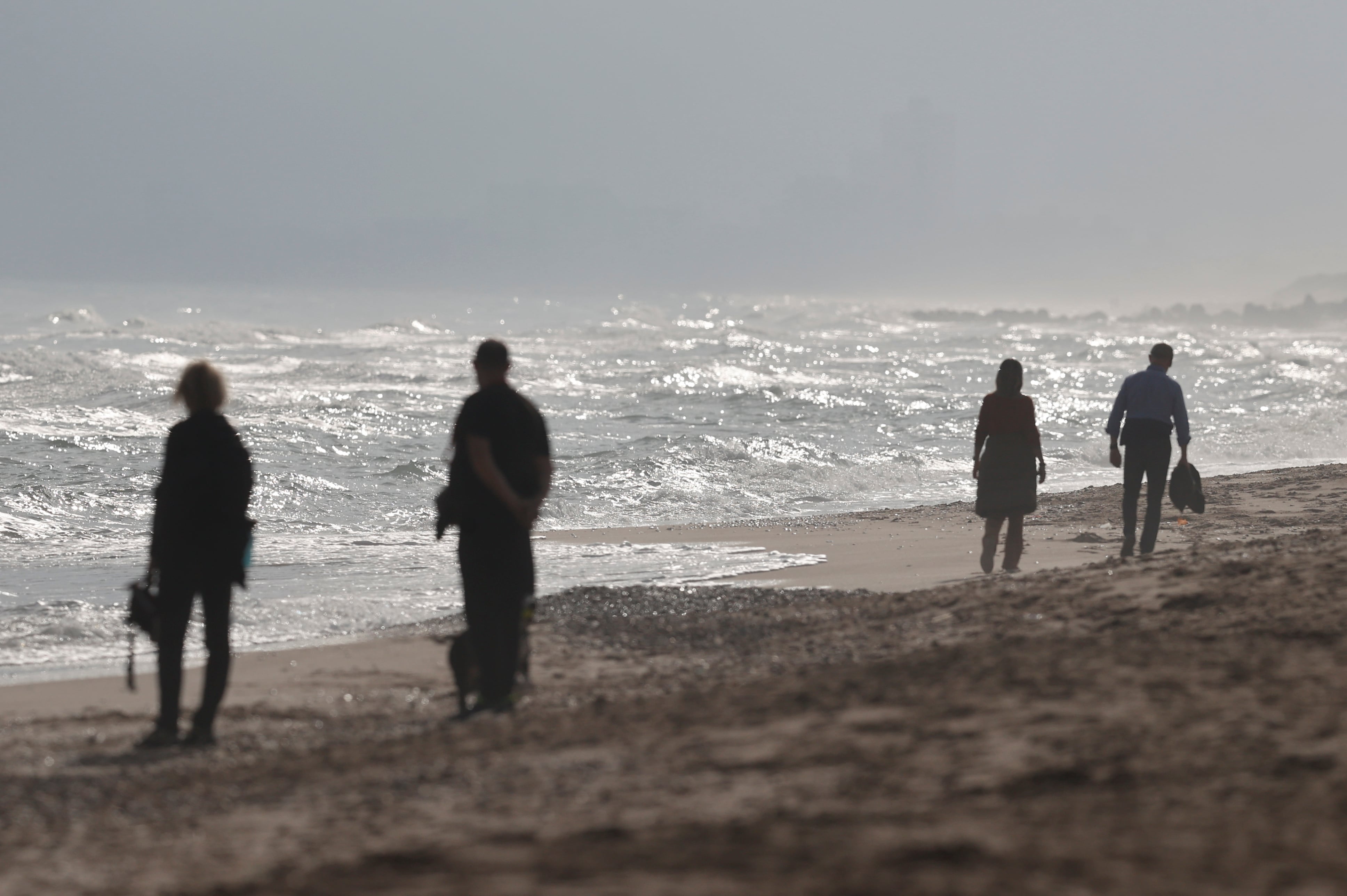 Varias personas aprovechan el día festivo para dar un paseo por la playa de El Saler en Valencia. El maratón de Valencia ha llevado a la ciudad hasta el 85% de ocupación media hotelera durante los primeros días del puente