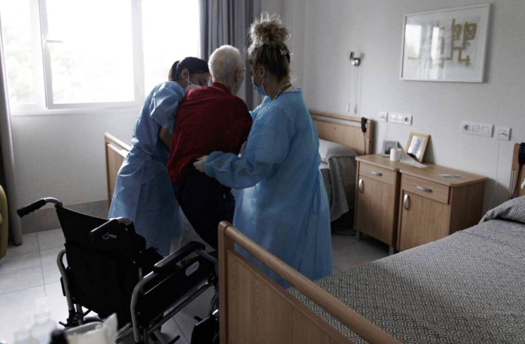 Sanitarias ayudan a un anciano en un centro de mayores