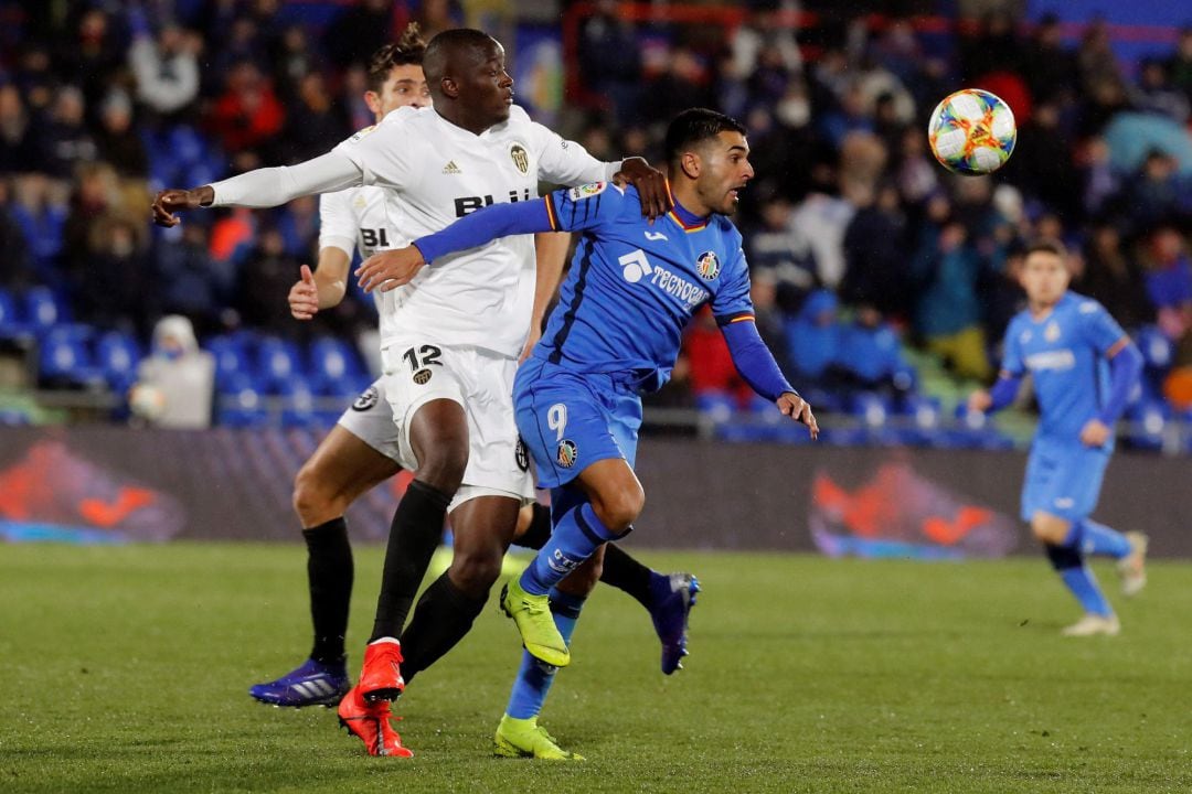 El delantero del Getafe Ángel Hernández (d) juega un balón ante Mouctar Diakhaby, del Valencia, durante el partido de ida de cuartos de final de la Copa del Rey que se disputa esta noche en el Coliseo Alfonso Pérez, en Getafe. 