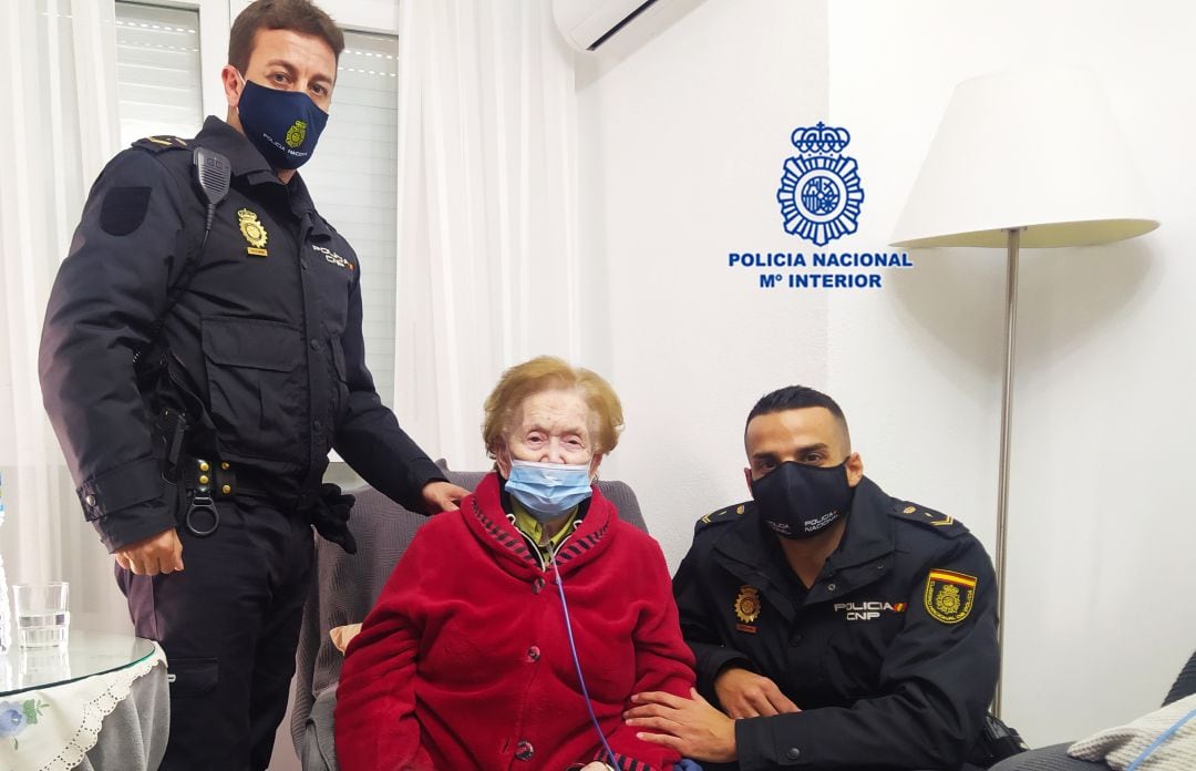 Los dos agentes de la Policía Nacional posan junto a la mujer a la que auxiliaron en su vivienda