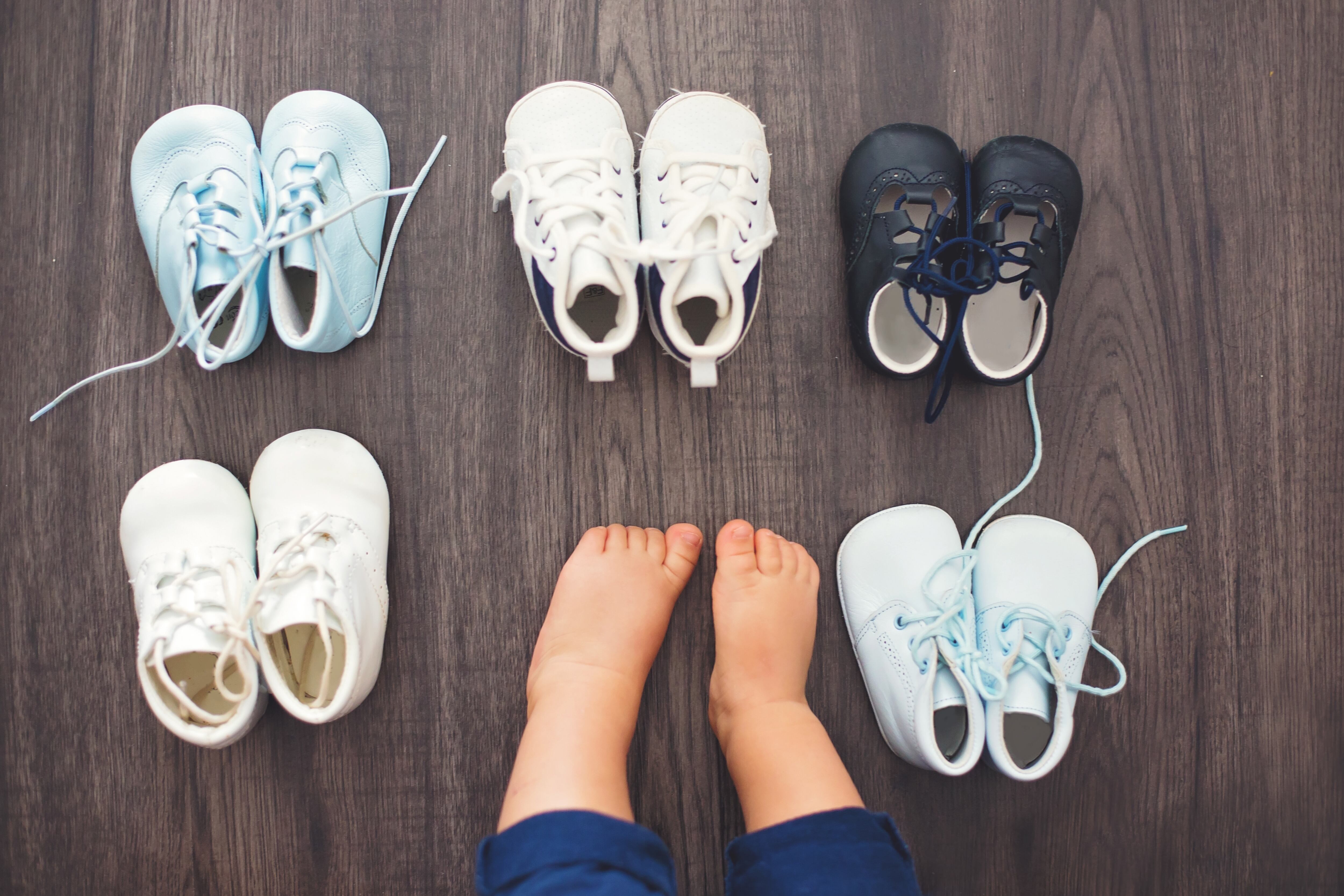 Children shoes and baby feet on a wood background, isolated