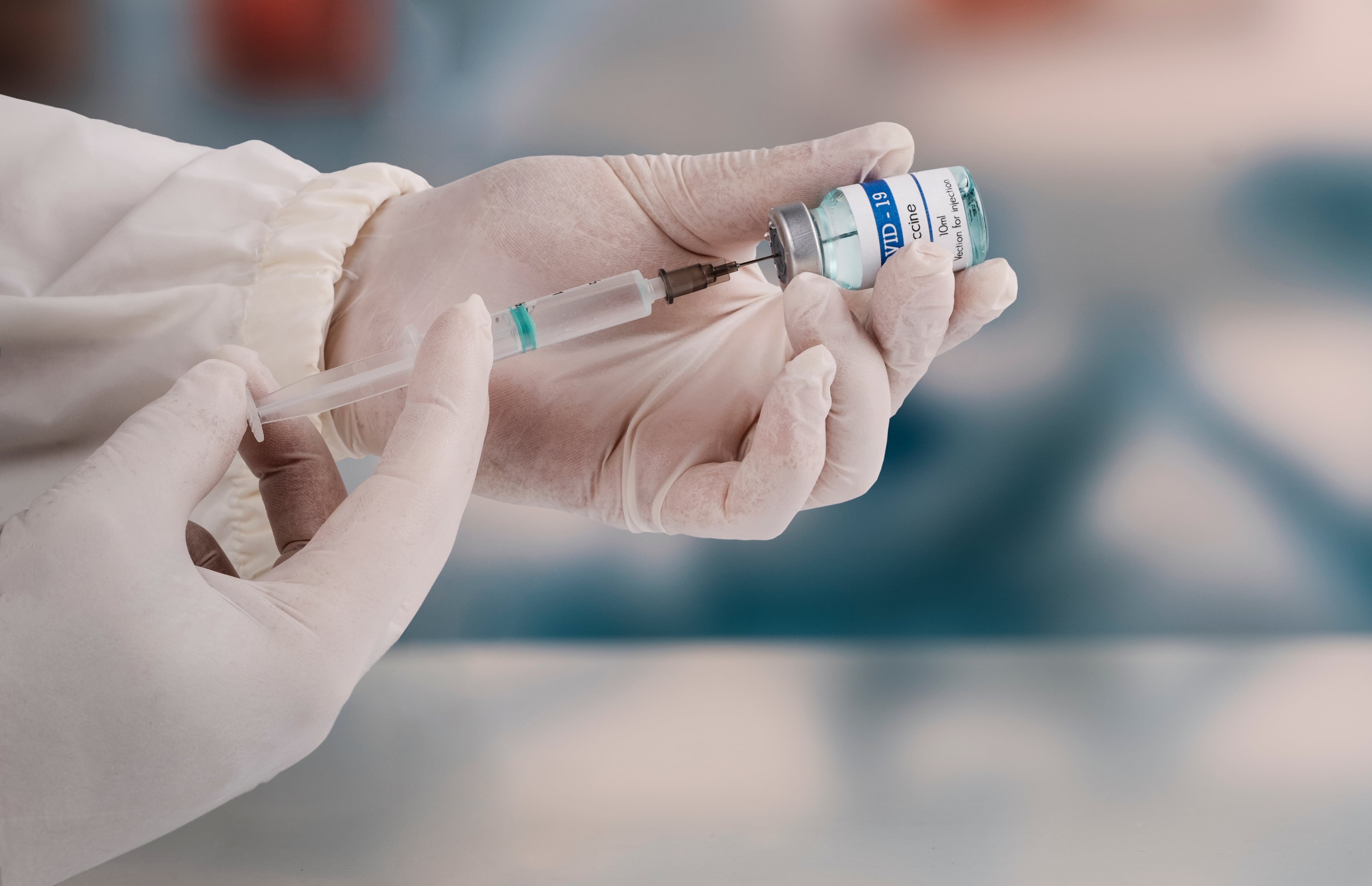 Using a syringe to attack the new covid-19 variant. A young doctor in a white protective glove holds a medical syringe and a vial.