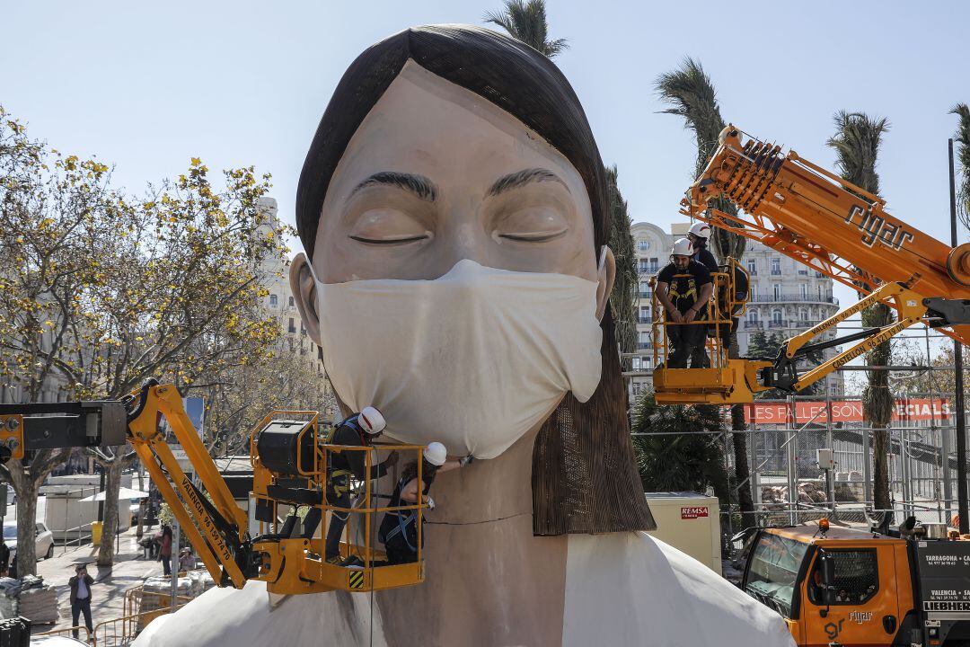 Foto del momento en que unos operarios colocan una mascarilla al busto de la meditadora en marzo de 2020