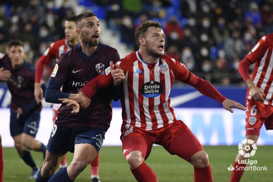 Diego Alende disputa un balón con Darío Poveda durante el encuentro correspondiente a la jornada 28 de la temporada 21/22 entre la SD Huesca y el CD Lugo.