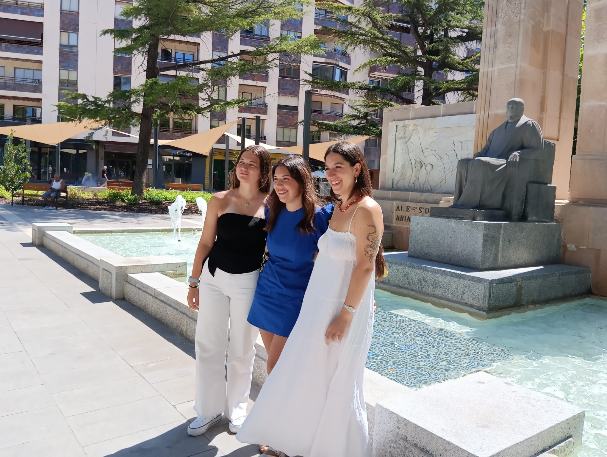 La reina, en el centro, Paula Carpintero Gil, posa con las damas, Claudia López Peña (izq) y Ana Velasco Cuenca, delante de la estatua de Don Diego