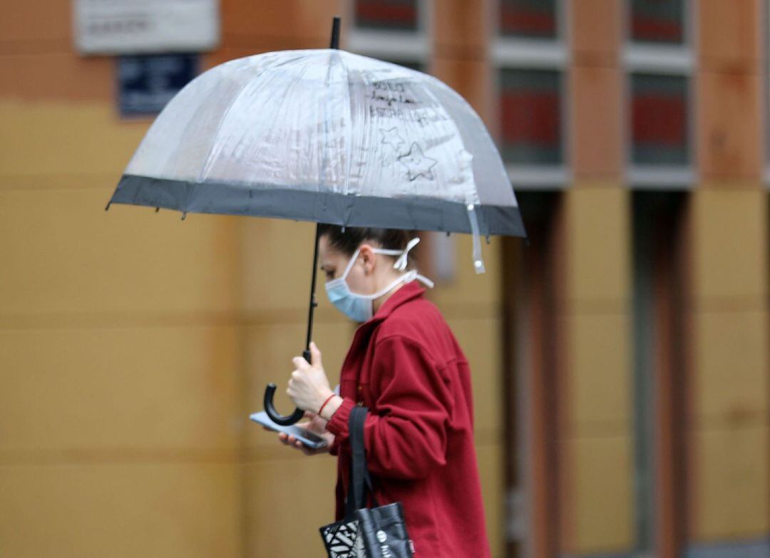 Una persona camina bajo la lluvia protegida con un paráguas, cuando las tres provincias de la Comunitat Valenciana permanecen este lunes en alerta amarilla por precipitaciones que podrían acumular 20 litros por metro cuadrado en una hora, según la Agencia Estatal de Meteorología (Aemet)