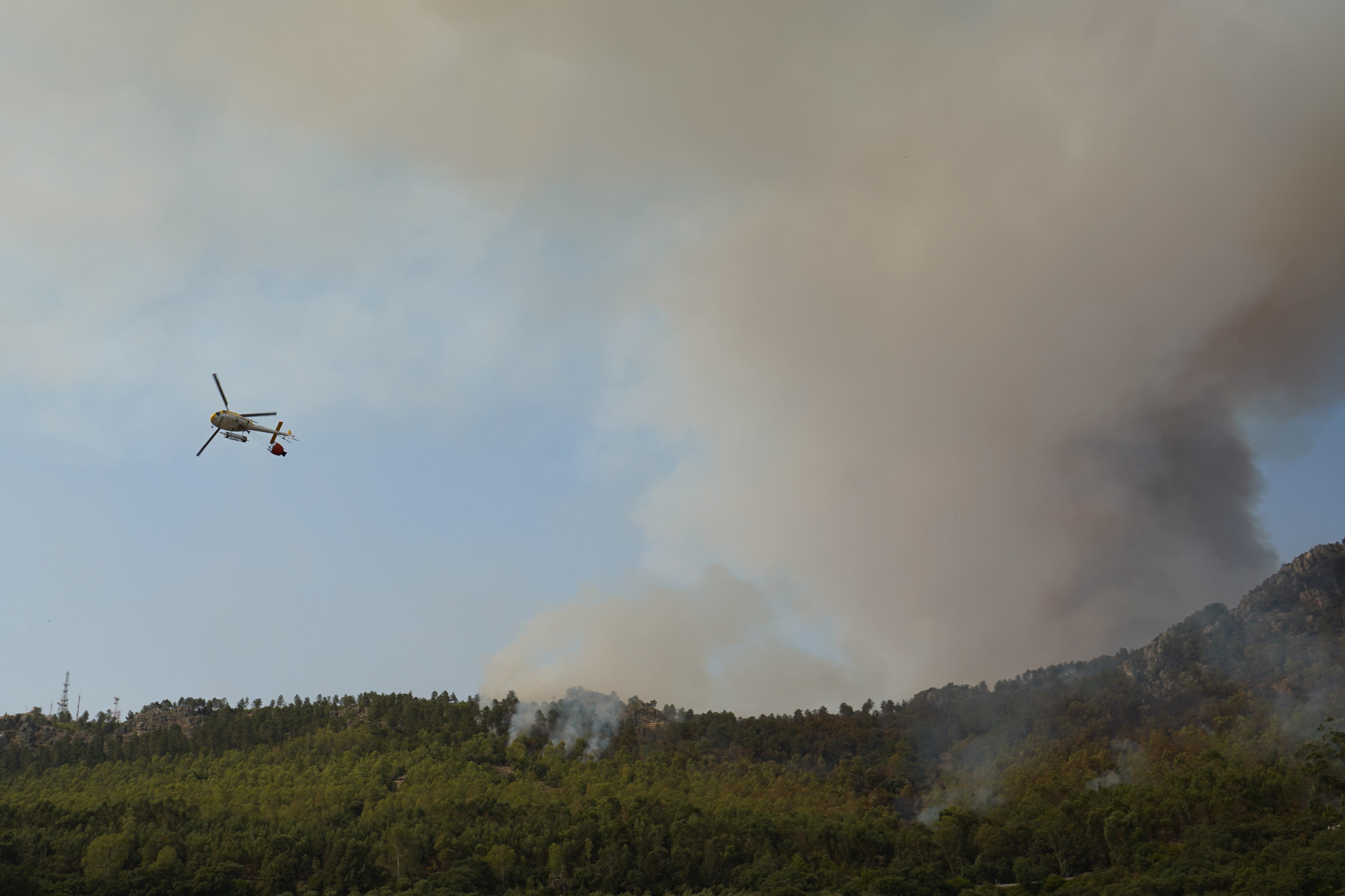 CASAS DE MIRAVETE, 15/07/2022.-Vista de un helicóptero trabajando en las labores de extinción de en de Casas de Miravete, localidad que ha tenido que ser desalojada esta noche, y que evoluciona de forma "no favorable", según ha informado este viernes la Junta de Extremadura. La localidad de Casas de Miravete, próxima al Parque Nacional de Monfragüe, fue evacuada sobre las dos de la noche, ha indicado el 112.EFE/Eduardo Palomo