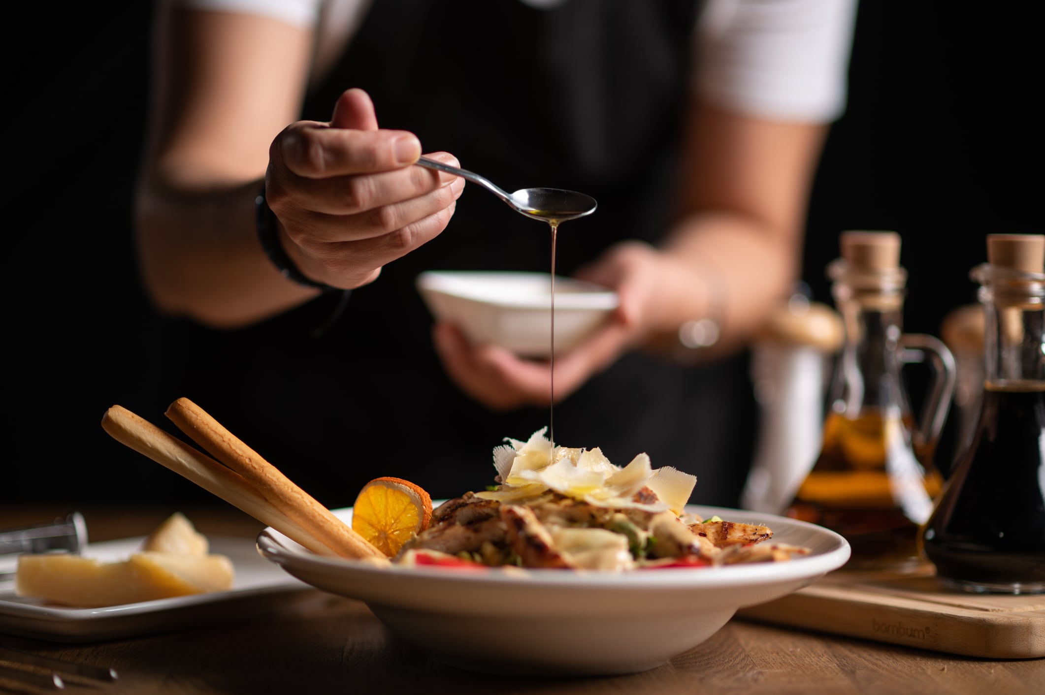 Una chef rocía de aceite de oliva un plato de comida