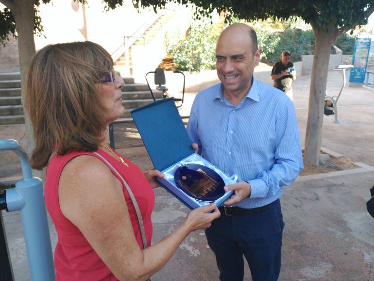 Gabriel Echávarri entrega una placa a la vecina Lola Pérez en agradecimiento por su colaboración con el barrio de Santa Cruz