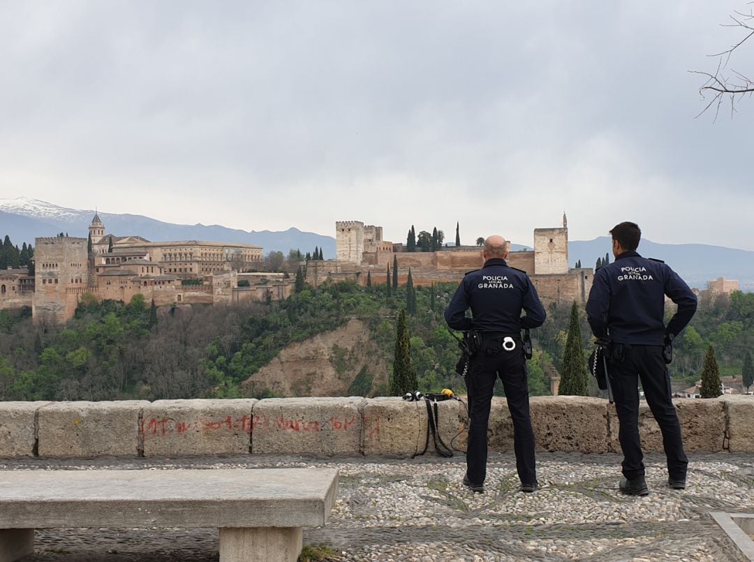 Agentes de la Policía Local de Granada vigilan en el Mirador de San Nicolás, uno de los puntos más concurridos por el turismo de la ciudad, para que se cumplan las normas del decreto de estado de alarma