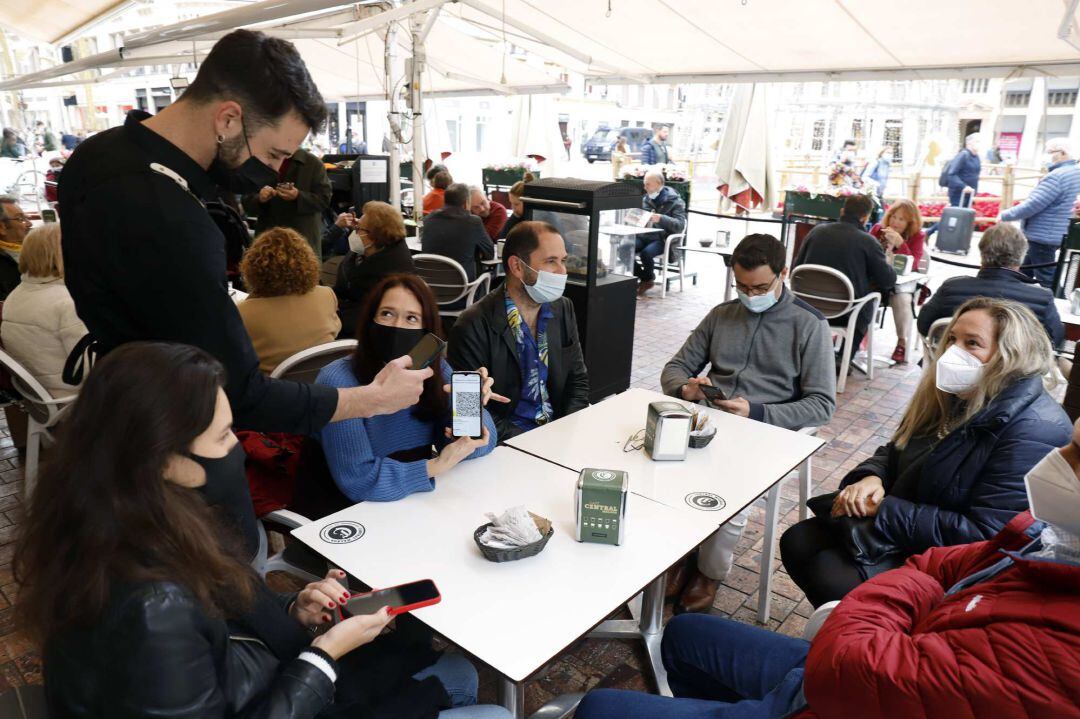 Un camarero pide certificado a los clientes en una mesa en la terraza de un bar 