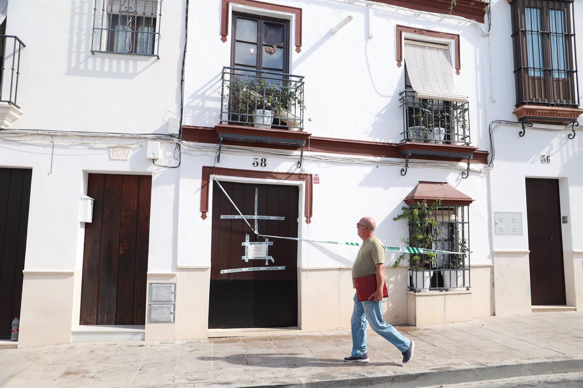 Un vecino camina ante la casa donde han sido hallados los cadáveres.