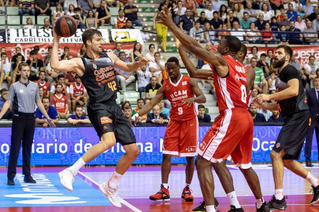 El alero canadiense del Valencia Basket, Aaron Doornekamp, intenta pasar la pelota a un compañero ante el alero británico del UCAM Murcia, Ovie Soko