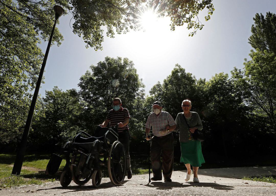 Dos personas mayores acompañados de un familiar caminan por el paseo del Arga, en la localidad navarra de Huarte, en una jornada donde continúa la fase de desesacalada que permite salir a la calle en diferentes horarios a los ciudadanos repartidos en diferentes tramos de edad.
