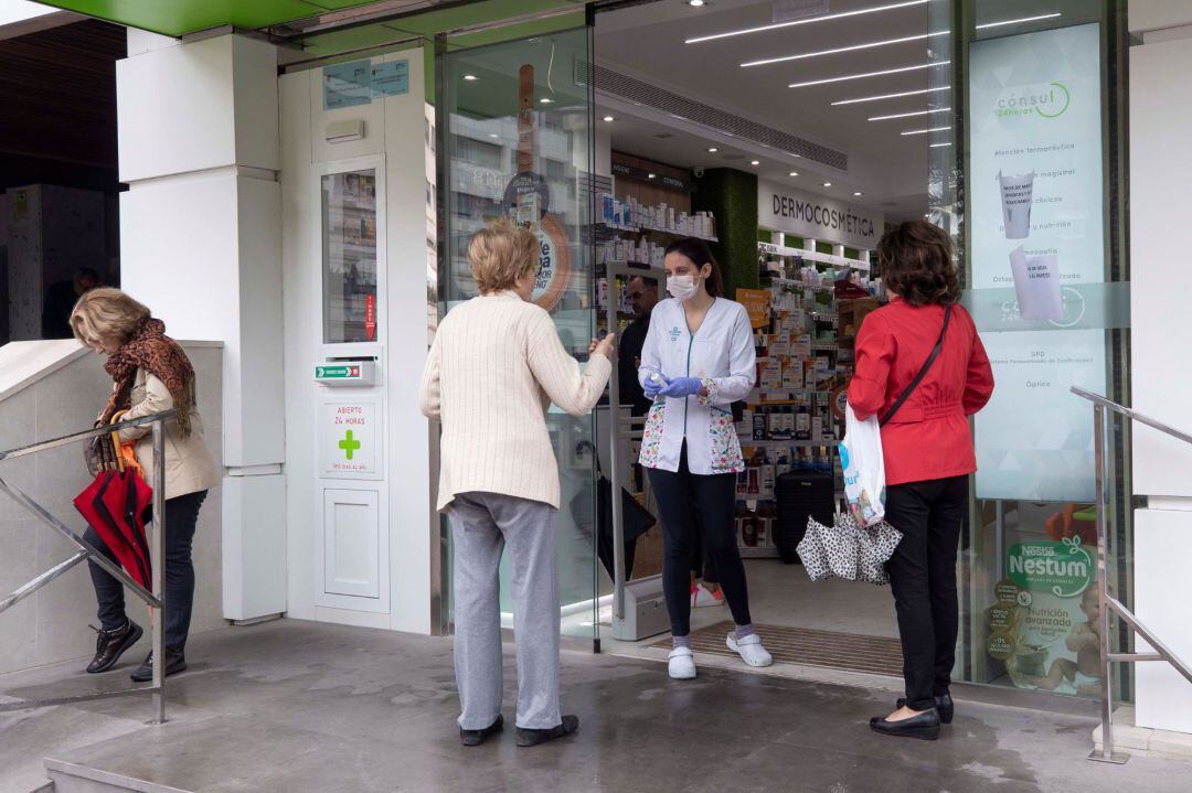 Una trabajadora de una farmacia atiende a los clientes en la puerta como medida de prevención por posibles contagios debido a la crisis del coronavirus, hoy en Murcia.