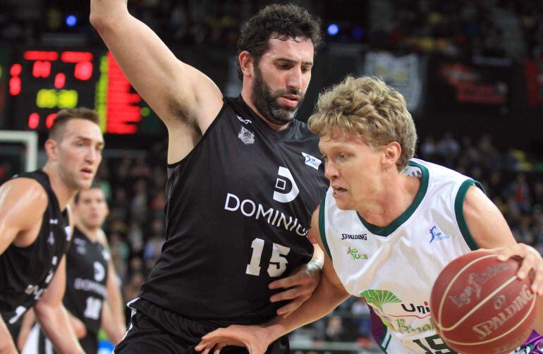 GRA490. BILBAO, 24/05/2015.- El alero del Dominion Bilbao Basket Álex Mumbrú (c) intenta bloquear al alero lituano del Unicaja Mindaugas Kuzminskas, durante el partido de la trigésimo cuarta jornada de Liga que disputan en el Bilbao Arena. EFE/LUIS TEJIDO.