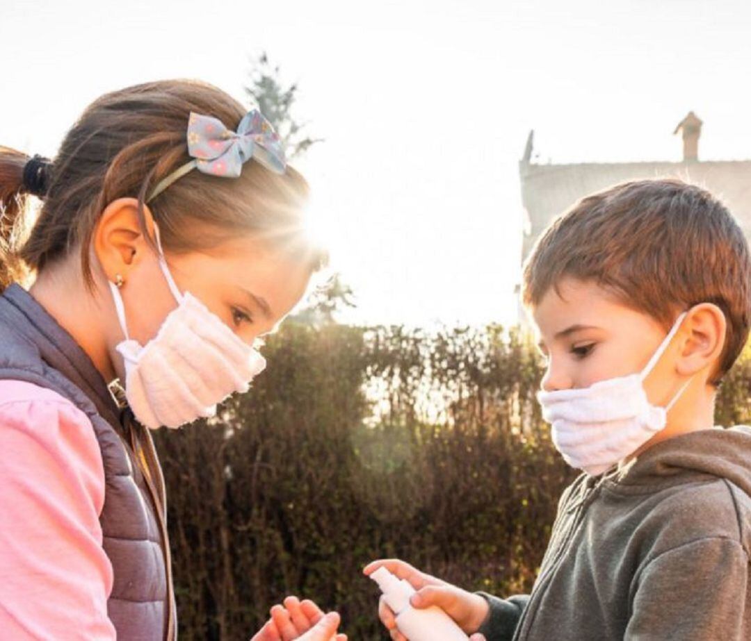 Dos menores con mascarilla, y gel hidroalcoholico
