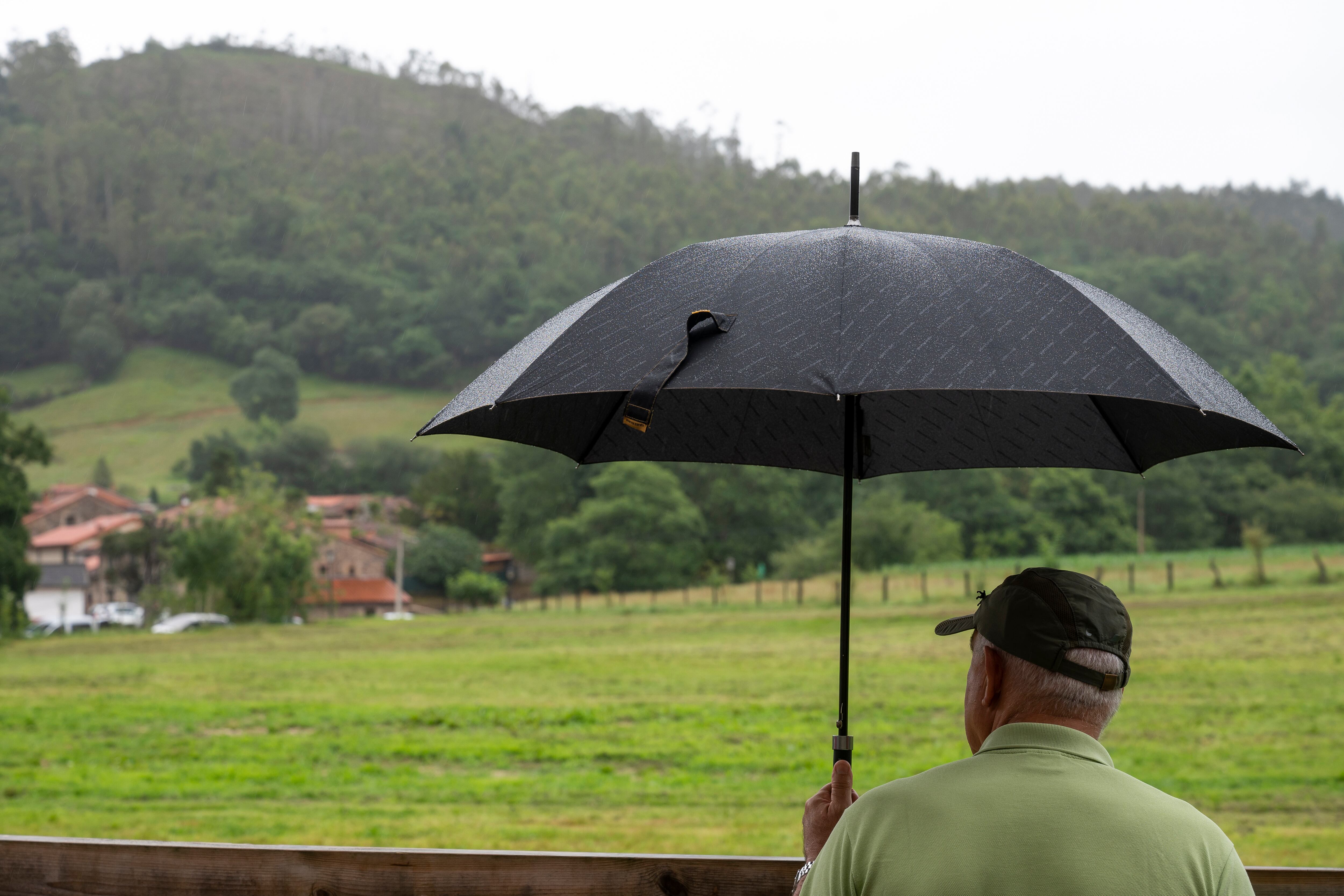 S002. Treceño (Cantabria) 15 julio 2023. Un hombre se cubre con un paraguas, este sábado, en la localidad cántabra de Treceño. EFE/Pedro Puente Hoyos
