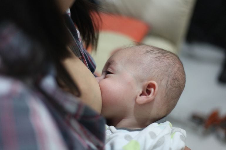 Una mujer amamantando a su hijo.