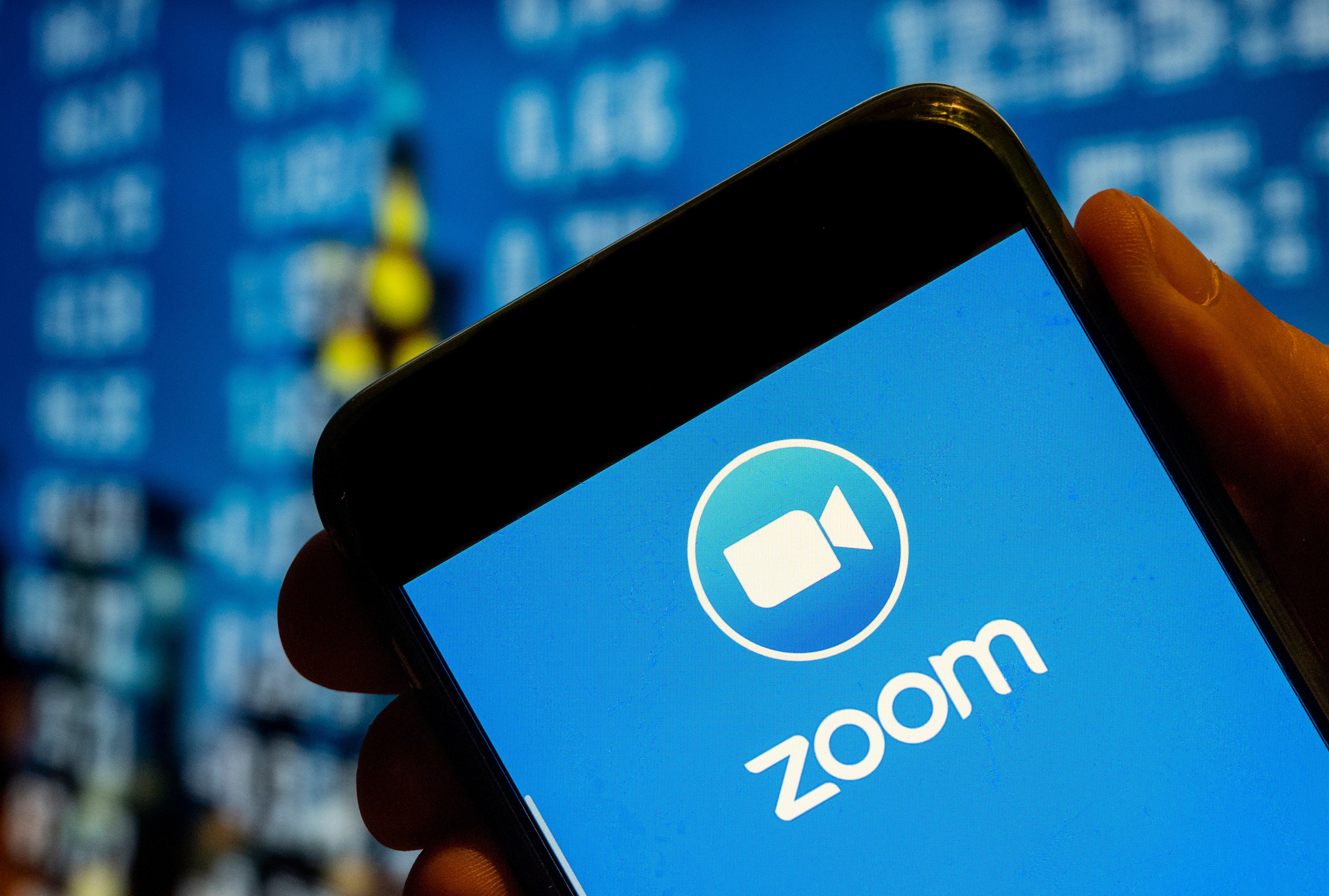 Una persona sujeta un móvil con la app Zoom.