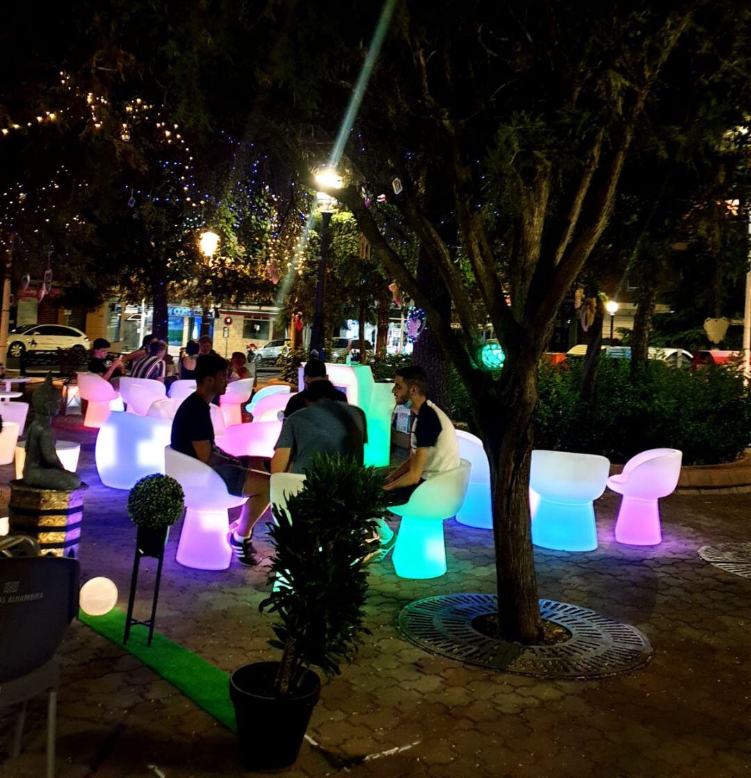 Sillas y mesas luminosas, guirnaldas en los árboles y hadas colgando de las ramas en una terraza de Puertollano