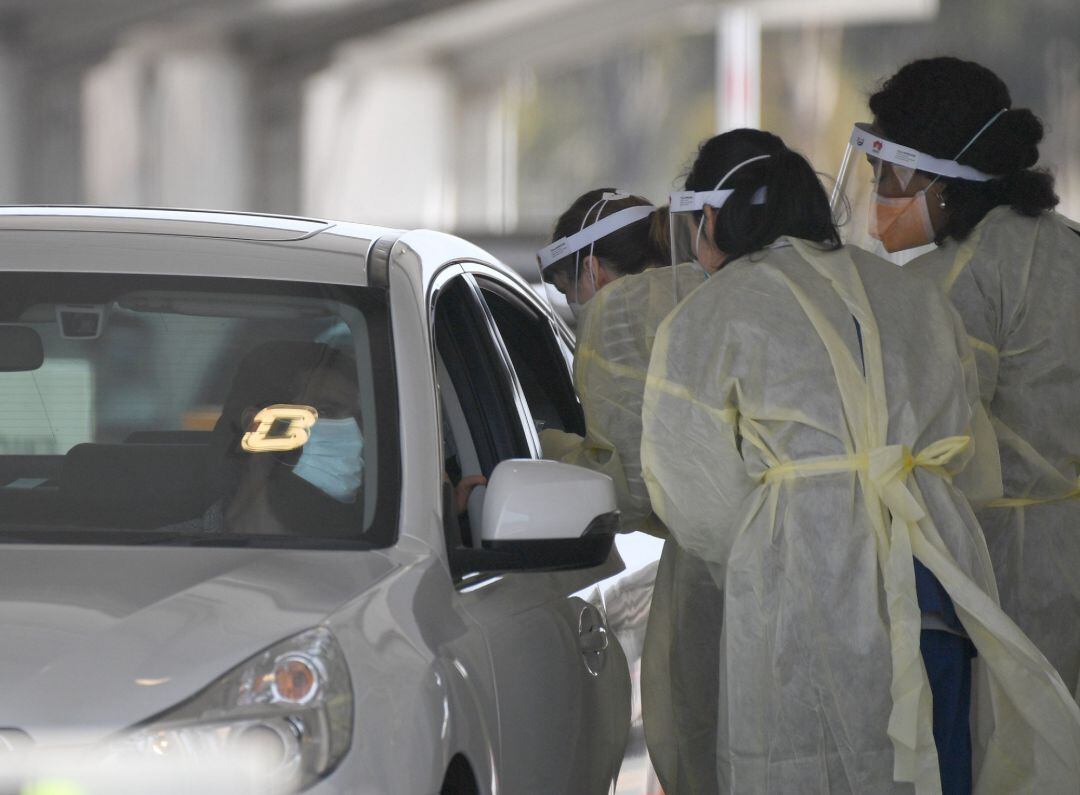 Varias sanitarias realizan una prueba PCR a un hombre.