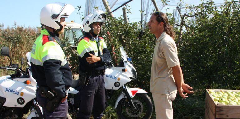 Una patrulla de mossos conversa amb un productor de pomes.