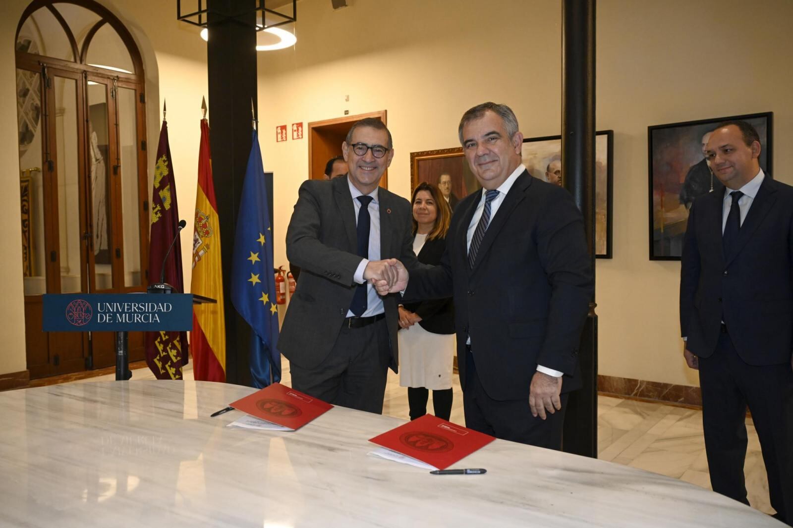 El rector de la UMU, José Luján, y el consejero de Universidades, Juan María Vázquez, estrechan la mano tras firmar el protocolo