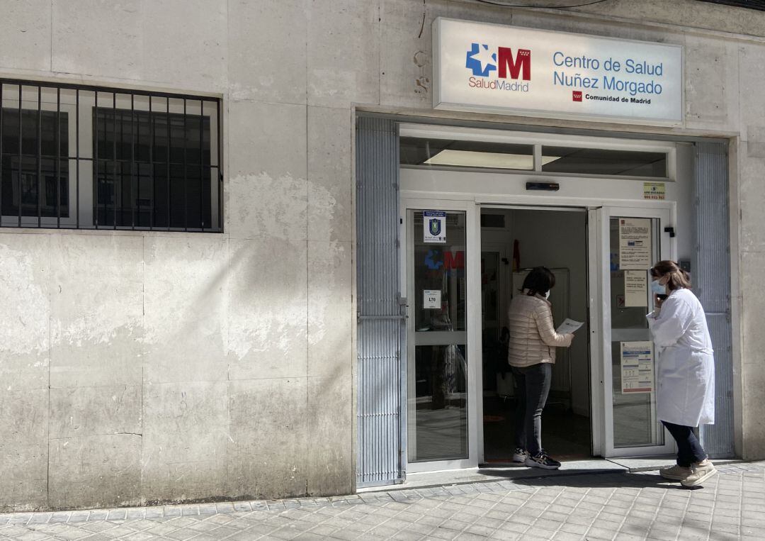 Archivo - Una mujer conversa con una trabajadora sanitaria en la puerta del Centro de Salud Núñez Morgado