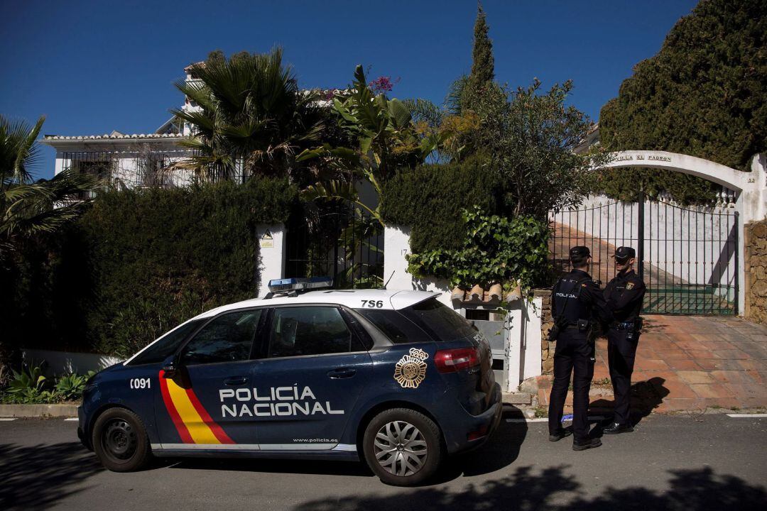 Dos miembros de la Policía Nacional custodian la vivienda donde anoche una mujer de 58 años y nacionalidad española fue asesinada tras ser apuñalada, en presencia de su hijo menor, en Estepona (Málaga) por parte de su marido, un ciudadano de 55 años del Reino Unido que se encuentra detenido e ingresado en un centro hospitalario tras provocarse lesiones. 