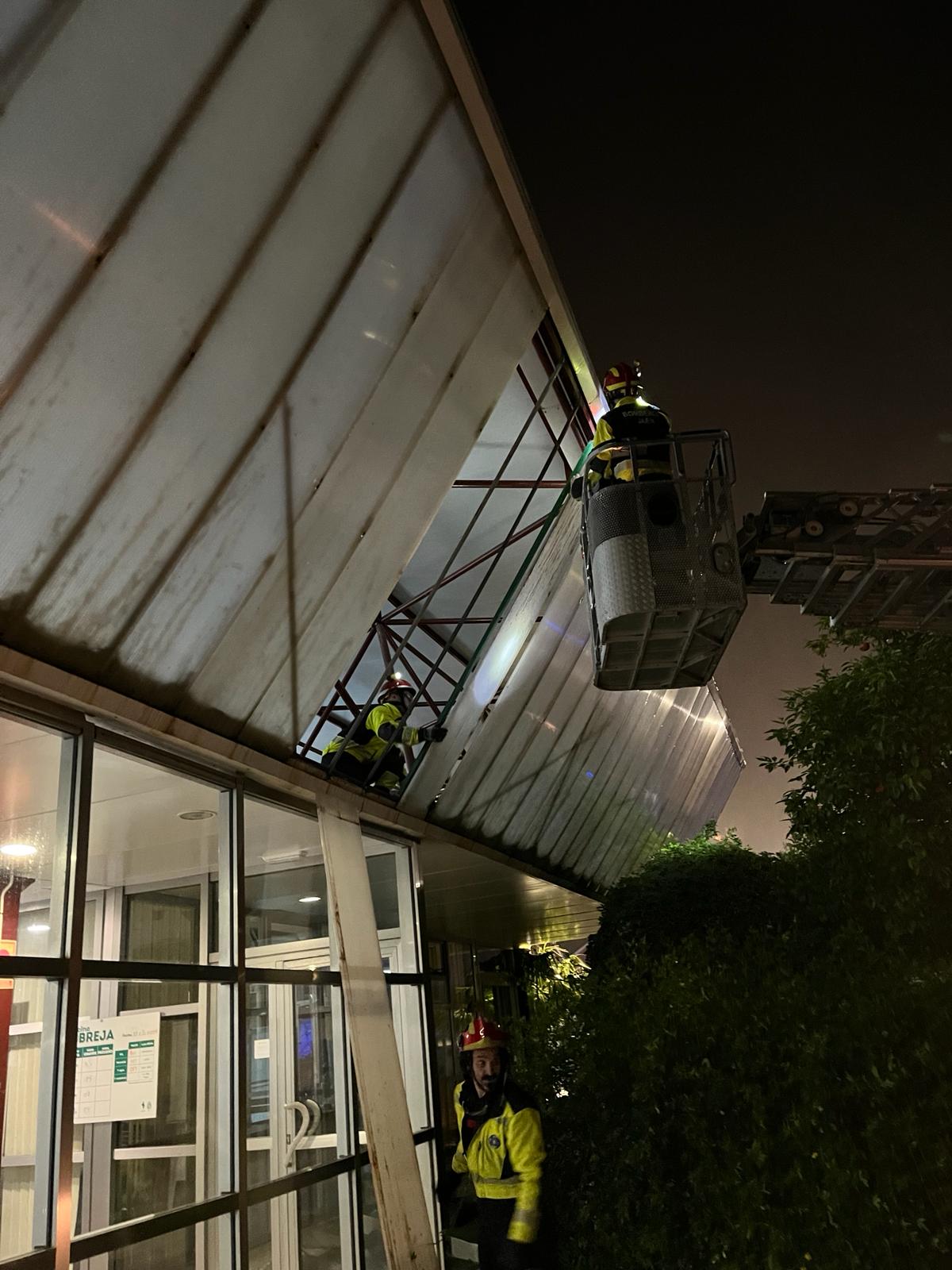 Los bomberos de Jaén trabajan para reparar los daños del viento en la fachada de la piscina de La Salobreja.