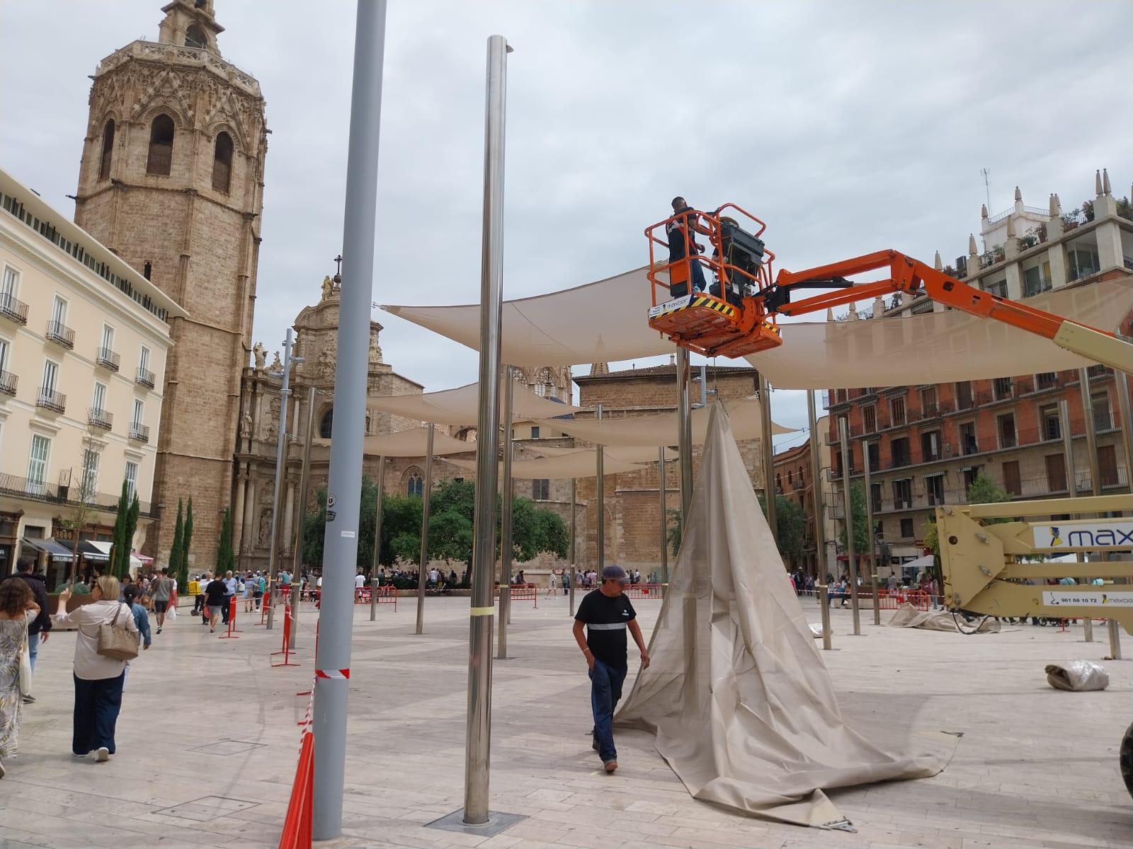 Los técnicos municipales colocan de nuevo los toldos de protección solar en la plaza de la Reina de València.