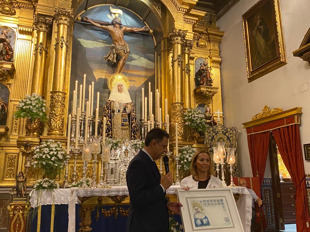 May Perea posa, junto al hermano mayor del Museo, con la papeleta de sitio que ha diseñado para la salida extraordinaria de la Virgen de las Aguas