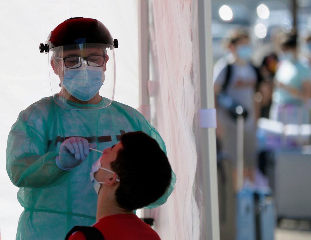 Un efectivo de Cruz Roja realiza una prueba PCR a un joven este jueves en Valladolid, momentos antes de subir al autobús que le lleva al campamento de verano