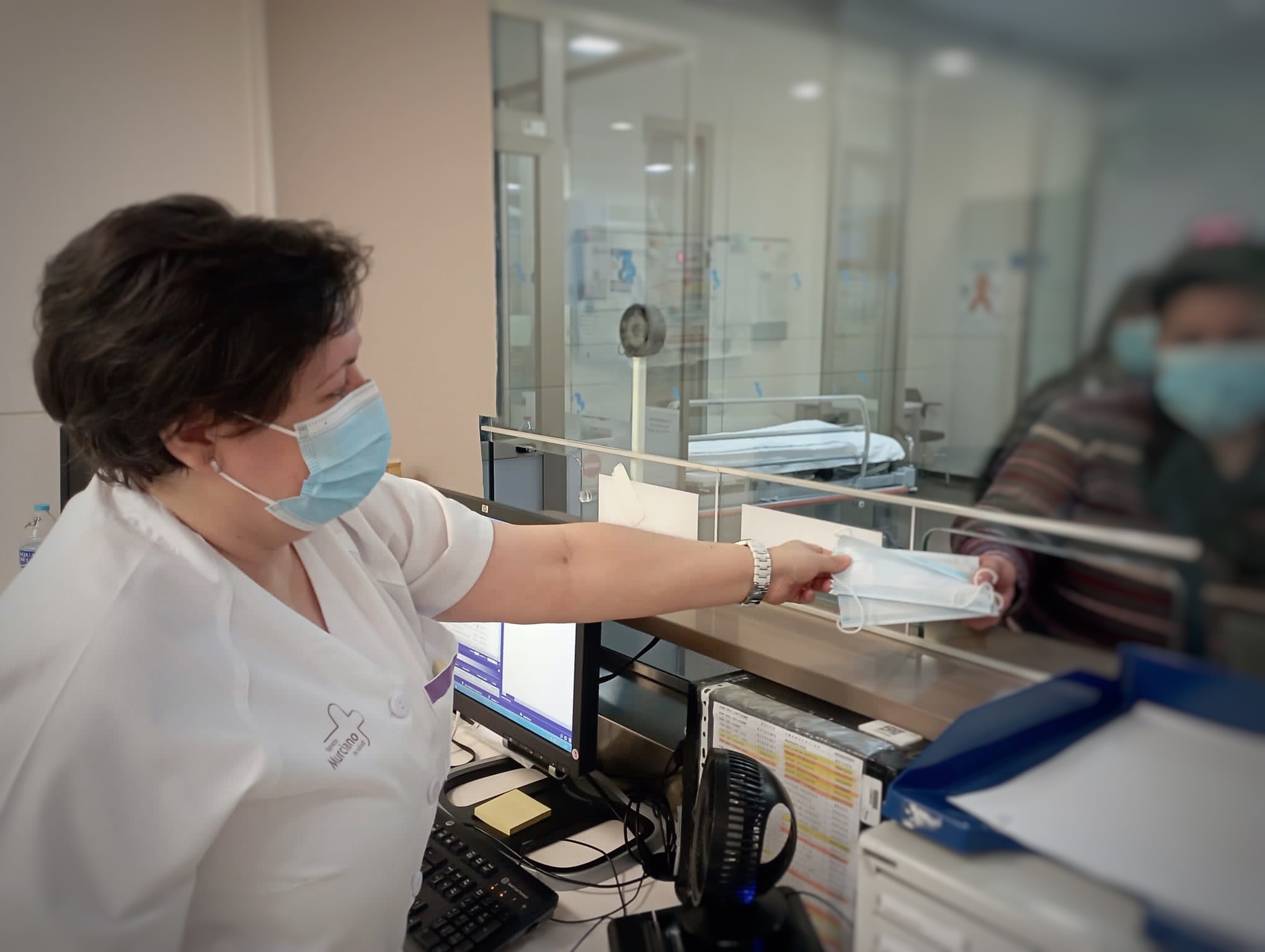 Una trabajadora ofreciendo mascarilla en un centro de salud