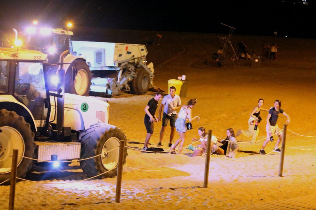 Un grupo de jóvenes son sorprendidos haciendo botellón en una playa de la Barceloneta, en una imagen de archivo