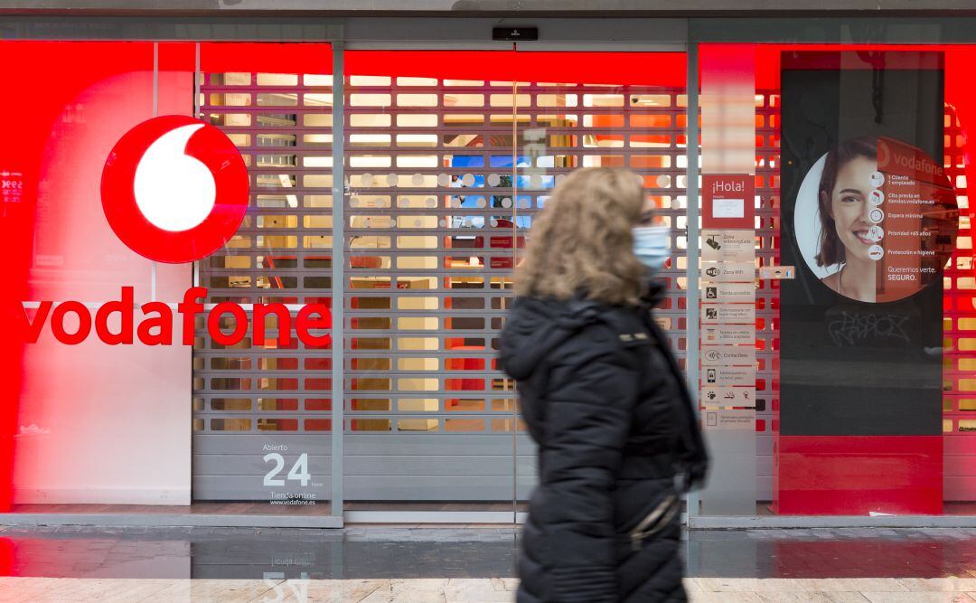 Una mujer pasea frente a una tienda de Vodafone.