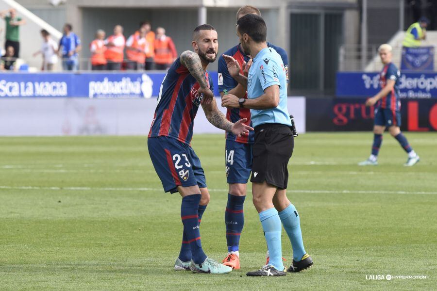 Los jugadores del Huesca protestan a González Frances que dio marcha atrás tras haber pitado penalti a favor de los oscenses