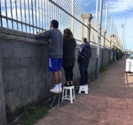 Gente viendo el partido desde el exterior de los campos