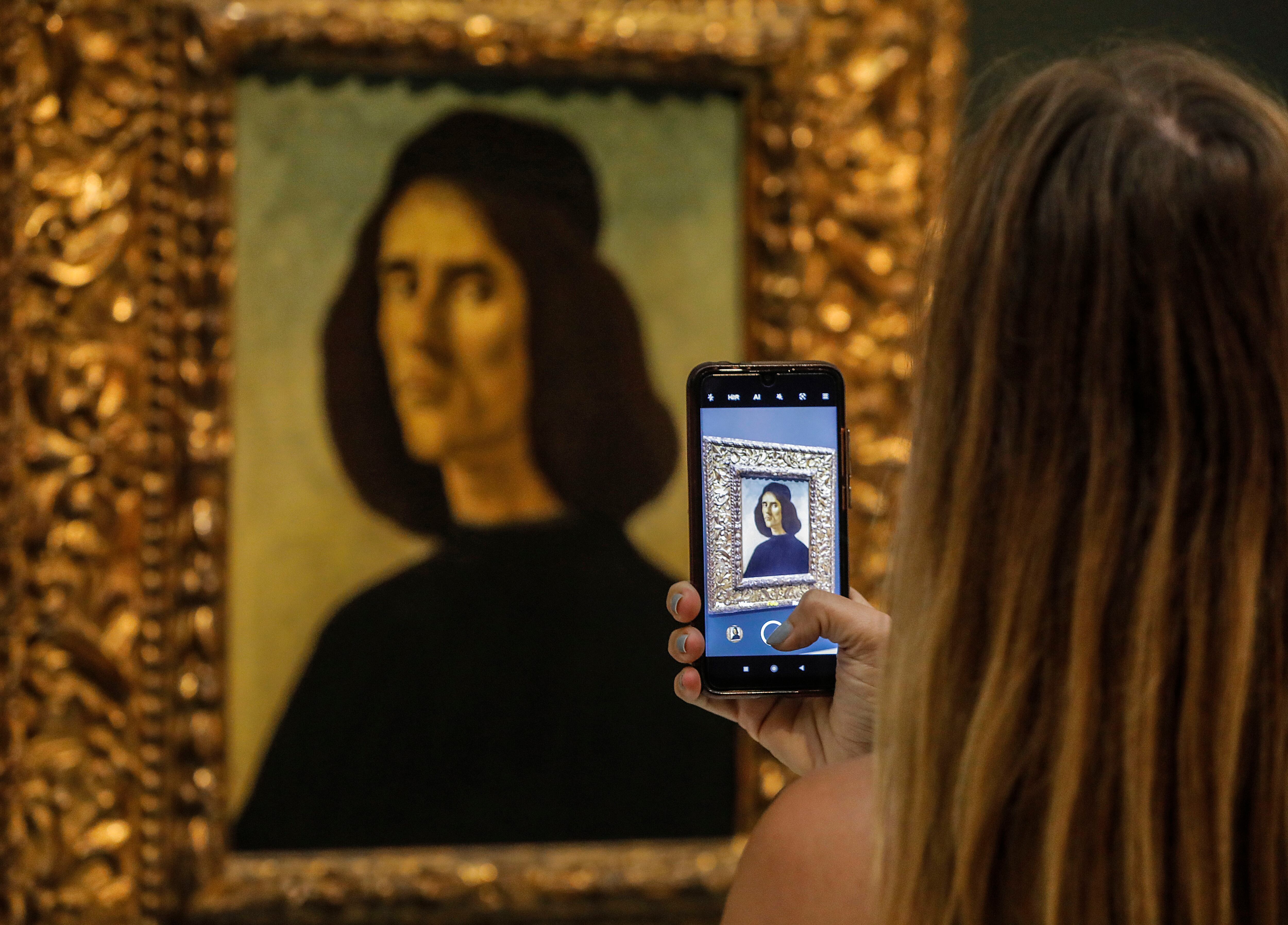 Una persona fotografía el &#039;Retrato de Michele Marullo Tarcaniota&#039;, de Sandro Botticelli en el Museo de Bellas Artes de València. El cuadro estará expuesto durante tres años y es el único retrato del pintor italiano en España.