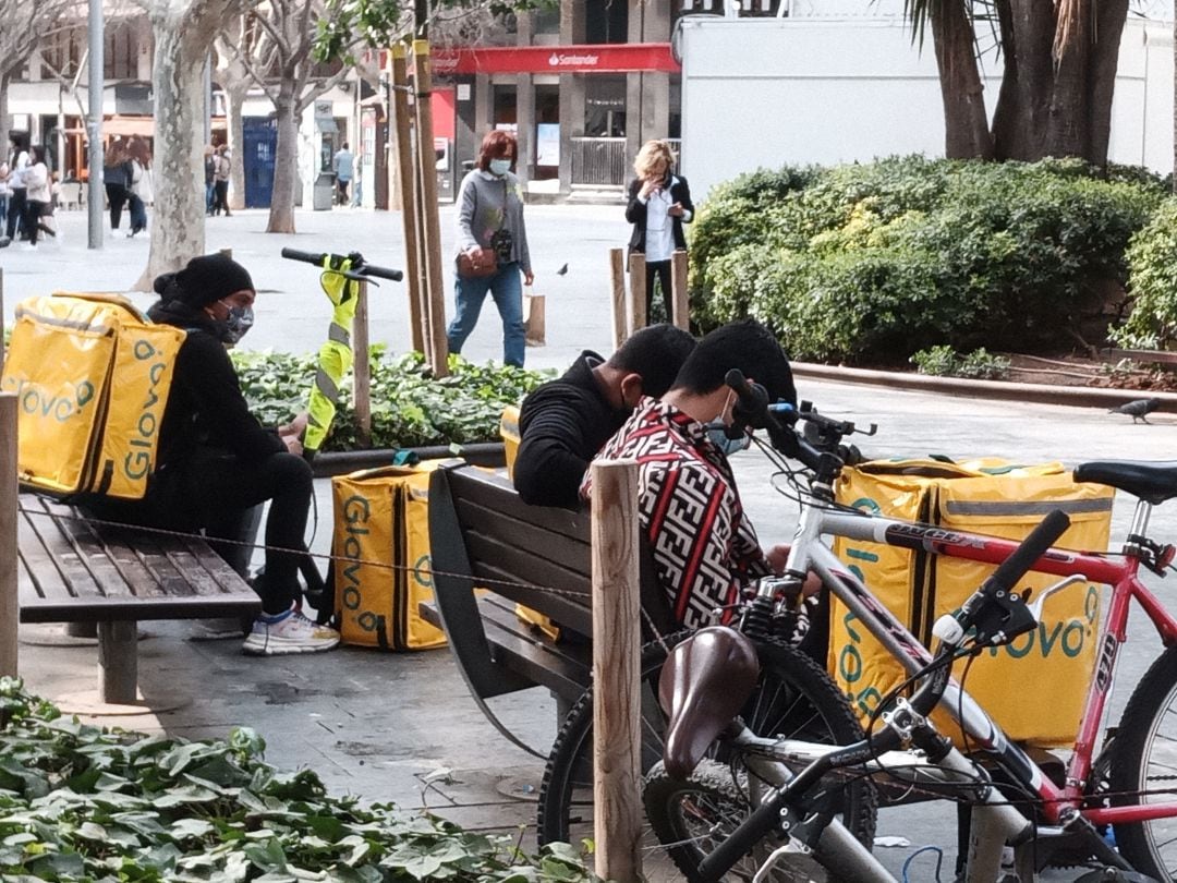 Un grupo de repartidores espera en Plaza de España para recibir un pedido.