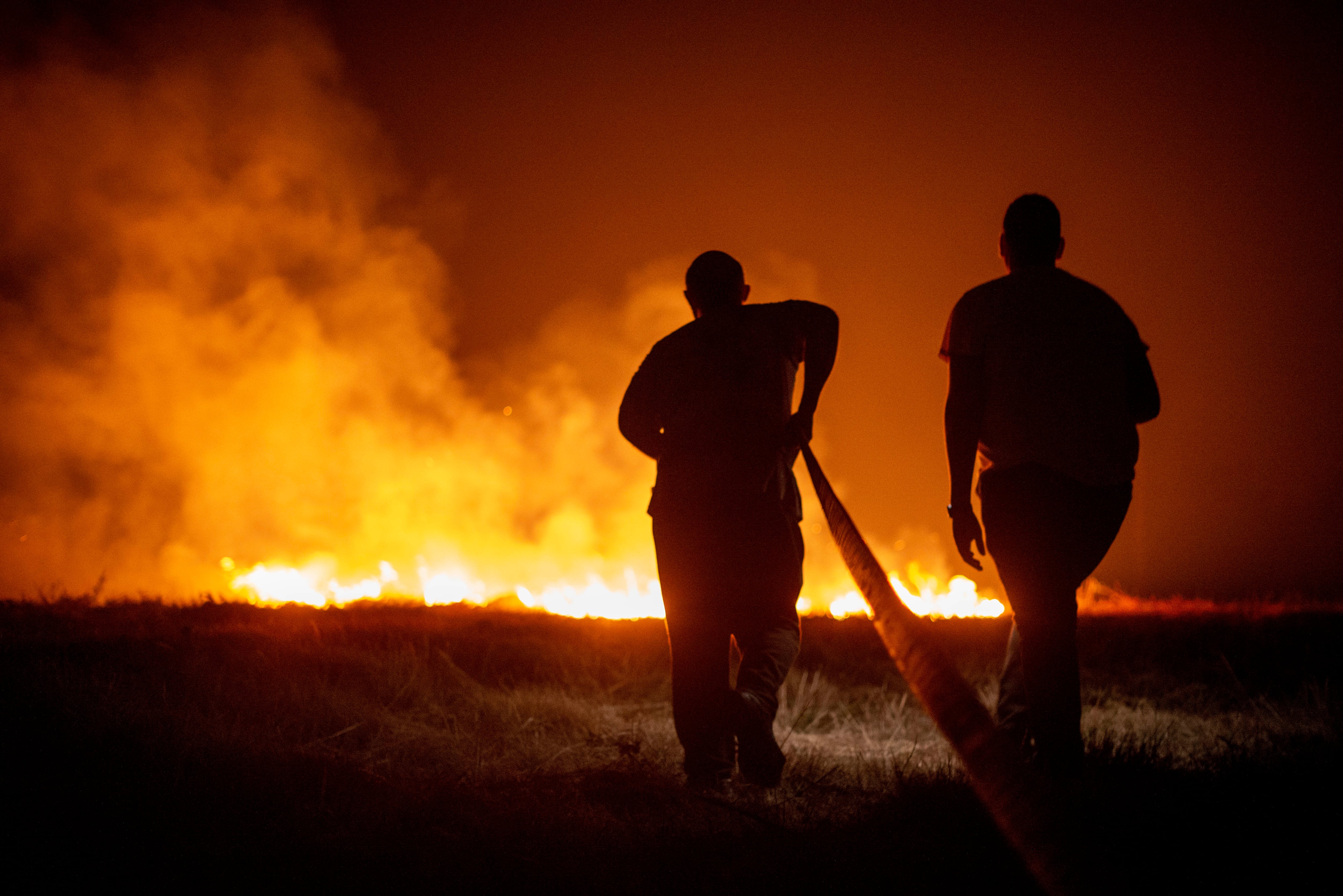BOIRO (A CORUÑA), 06/08/2022.- Dos vecinos colaboran la madrugada de este sábado en las labores de extinción del incendio de Cures, en Boiro, A Coruña. EFE/Brais Lorenzo